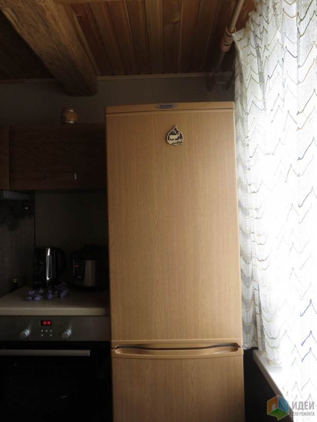 Отдельностоящий холодильник на угловой кухне под дерево