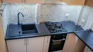 Дизайн маленькой кухни 7 кв.м с мозаичным фартуком и черной столешницей-подоконником