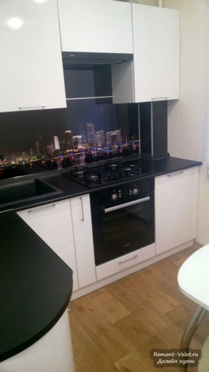 Дизайн белой кухни 5 кв.м с черной столешницей и холодильником в нише