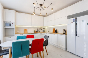 Дизайн белой кухни 15 кв м с деревянной столешницей и яркими стульями
