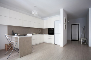 Современная белая кухня с фасадами без ручек в квартире-студии