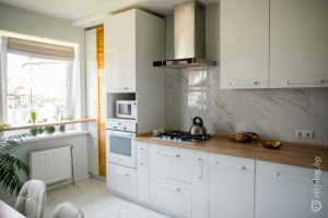 Белая кухня-столовая в скандинавском стиле с двумя окнами и диваном